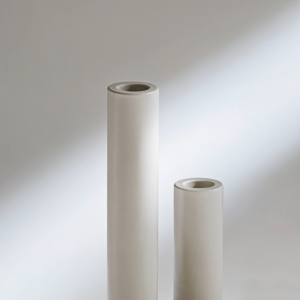 Textured cylindrical plaster vase displayed on a raw industrial brushed steel accent table, ideal for residential architecture portfolios and avant-garde editorial curation.